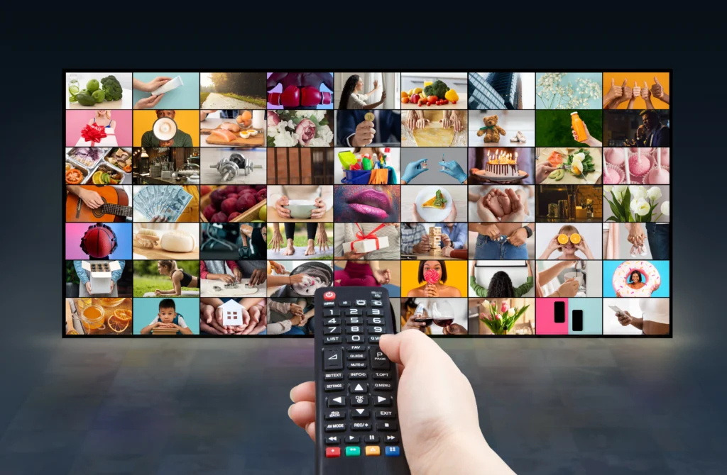 hand holding remote control large television displaying multiple images